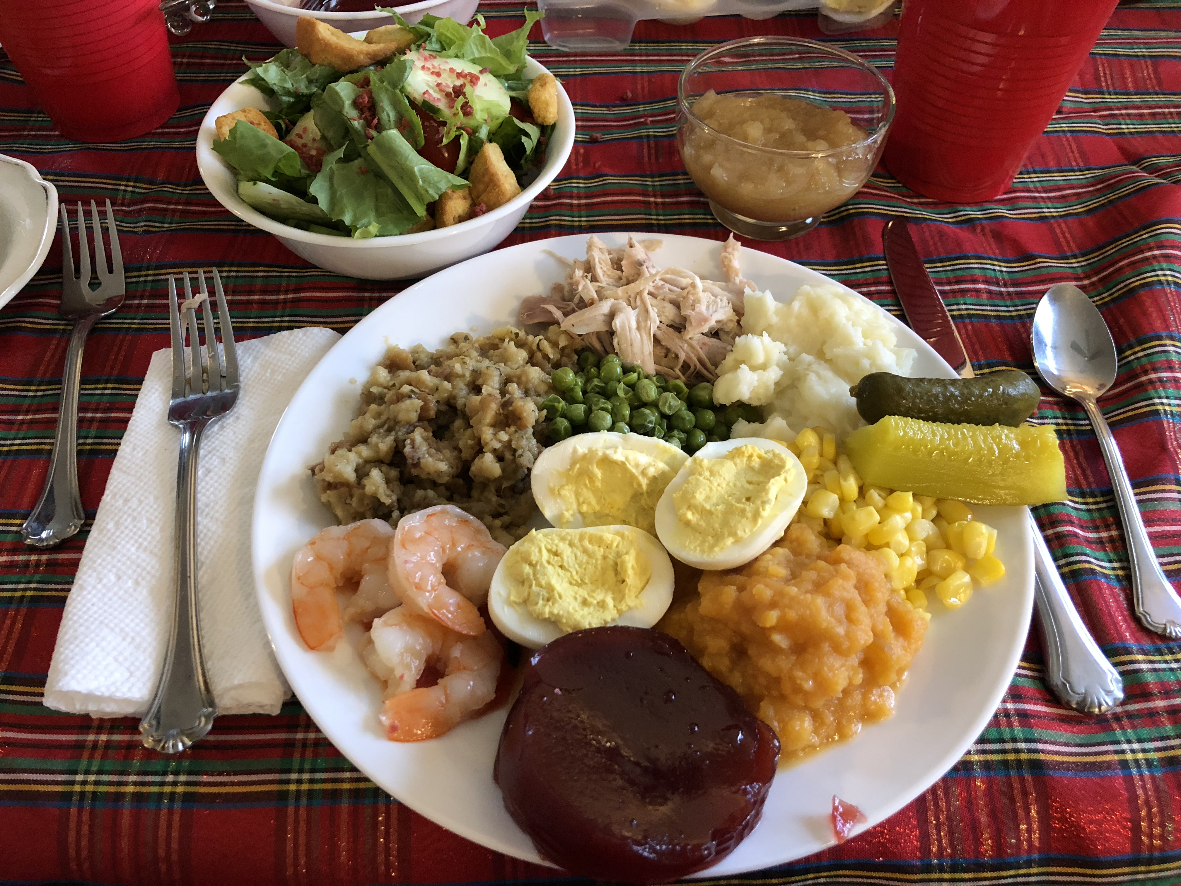 Sebuah makan malam Thanksgiving dengan kalkun panggang, kentang tumbuk, acar, jagung, ubi manisan, jeli kranberi, udang, isian, kacang polong, telur iblis, salad hijau, dan saus apel.