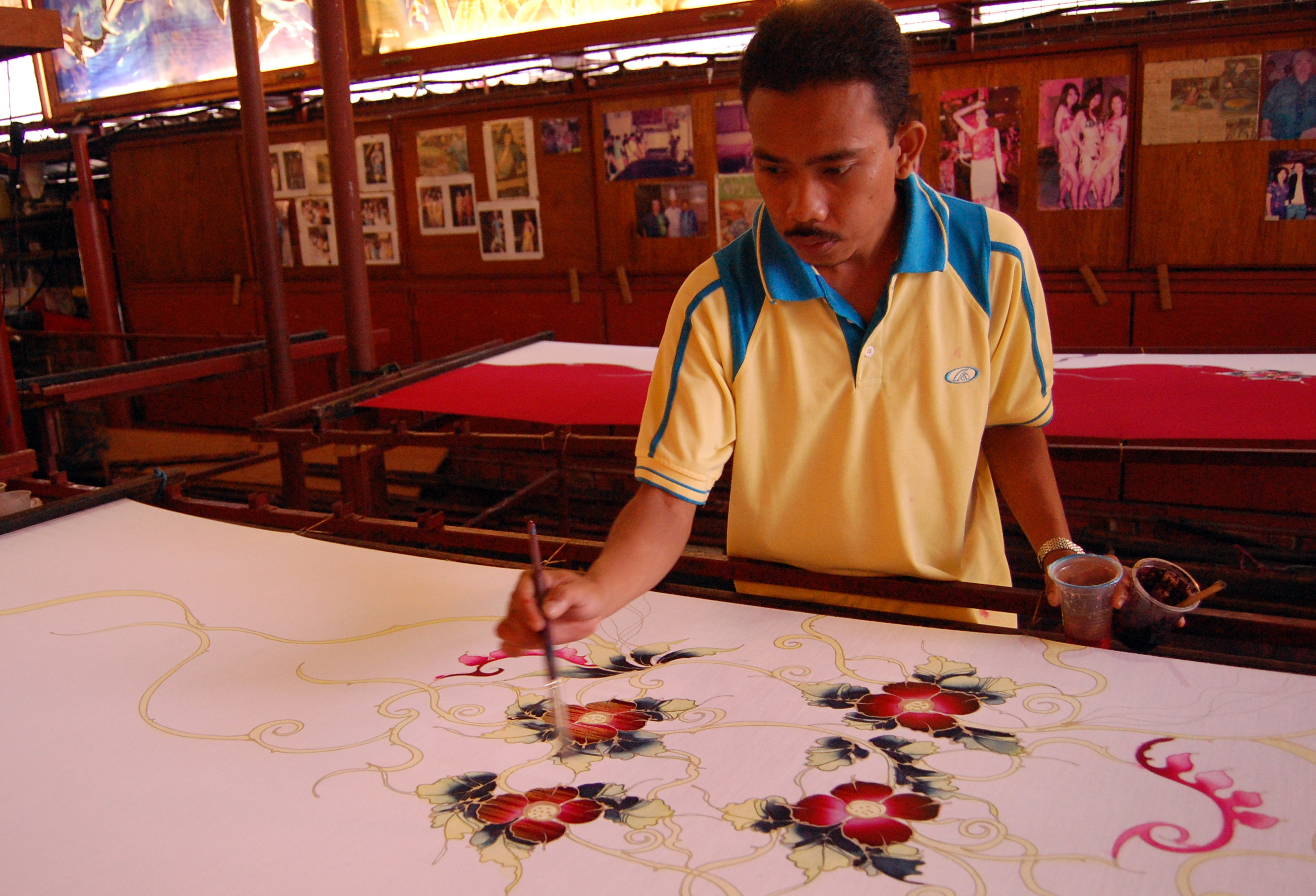 Seorang tukang membuat batik. Batik Malaysia biasanya bercorak motif bunga dengan pewarnaan terang.