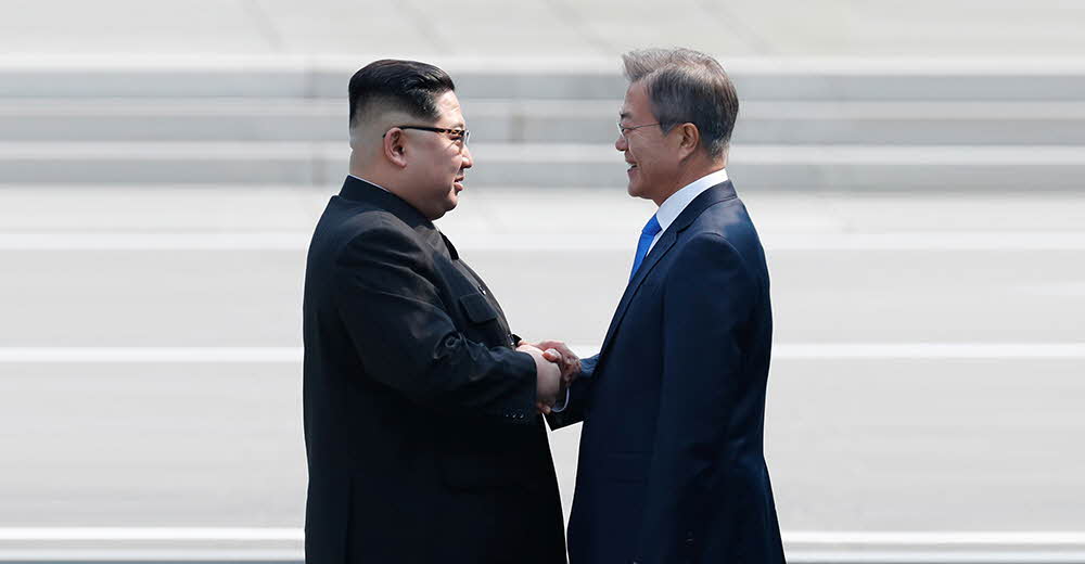 북한 지도자 김정은과 대한민국 문재인 대통령이 평화의 집 내부에서 악수하고 있다.