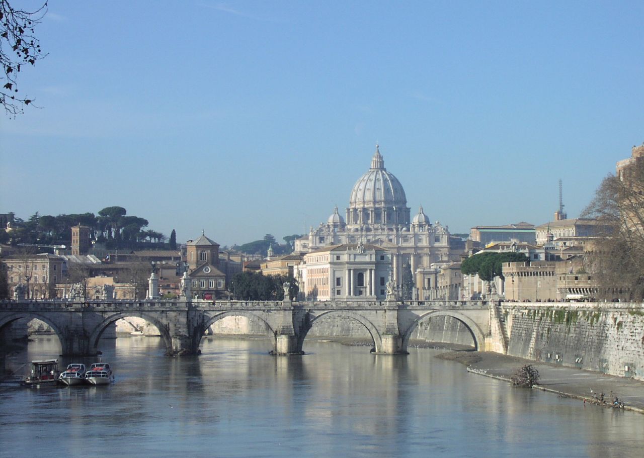 Basilika Santo Petrus dilihat dari Tiber; Bukit Vatikan di belakang dan Castel Sant'Angelo di Roma di sebelah kanan. Baik basilika maupun bukit tersebut merupakan bagian dari negara berdaulat Kota Vatikan, Takhta Suci Gereja Katolik.