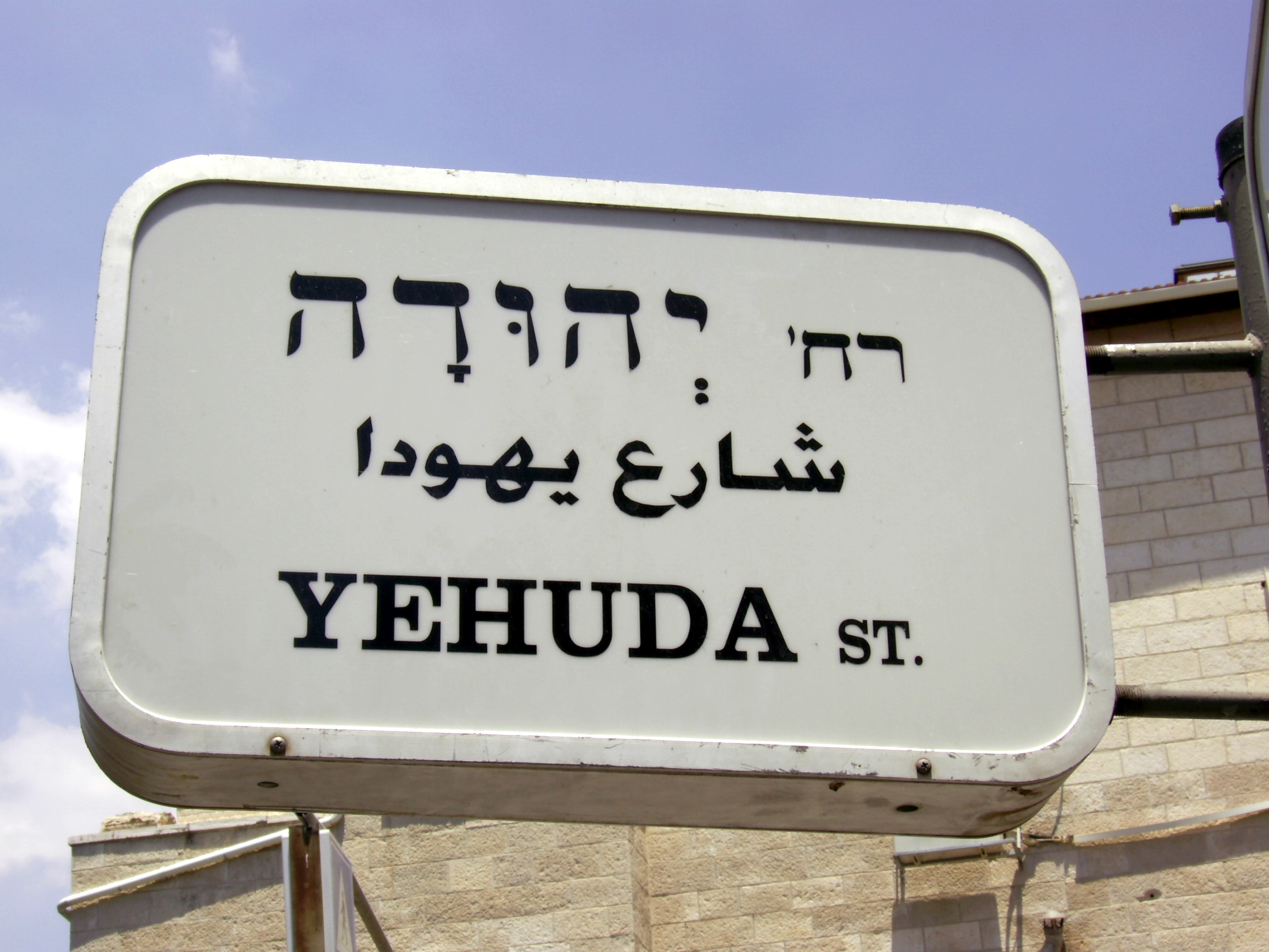 Road sign in Hebrew, Arabic, and English, reflecting Israel's linguistic landscape.