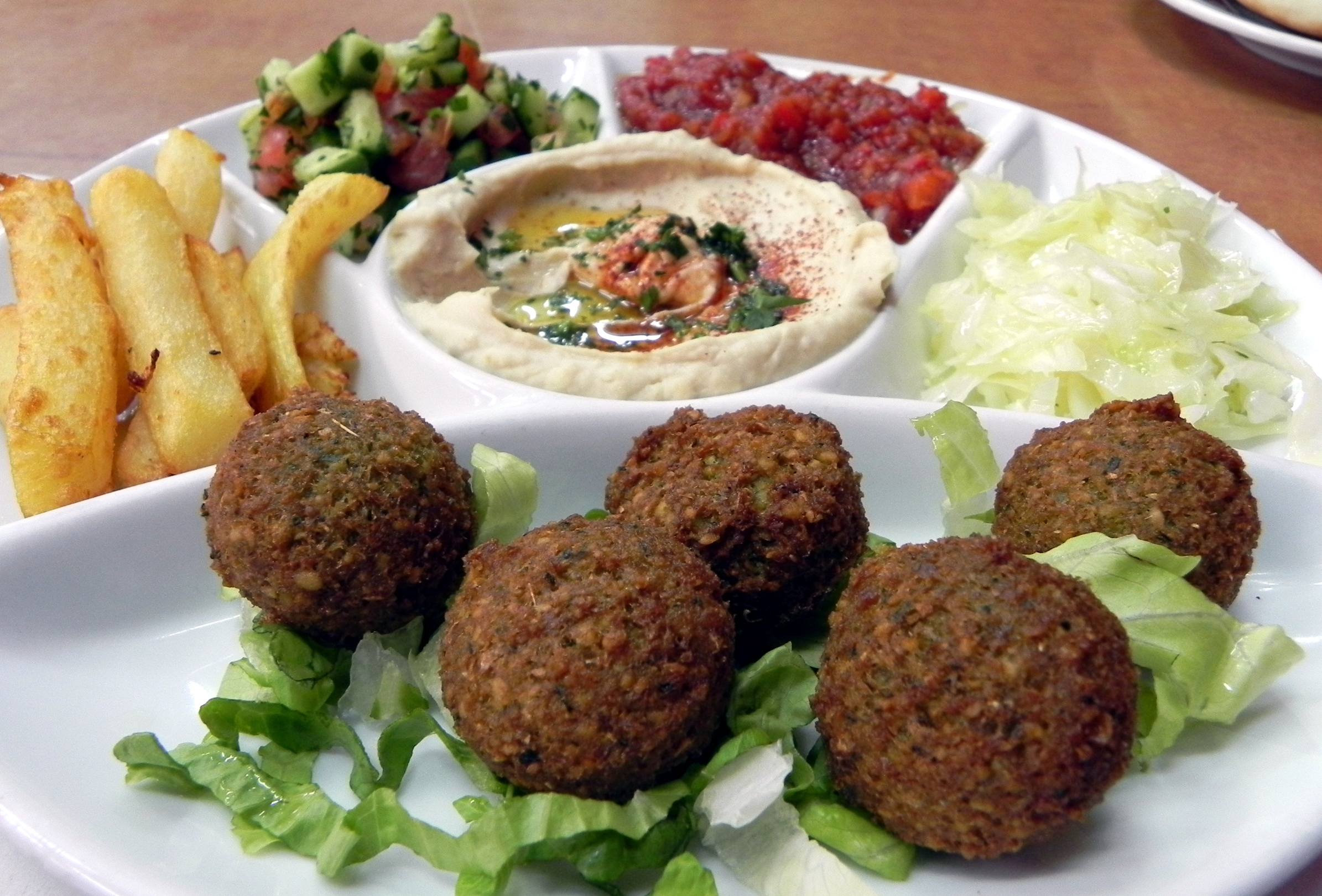 A typical Israeli meal featuring falafel, hummus, French fries, and Israeli salad.