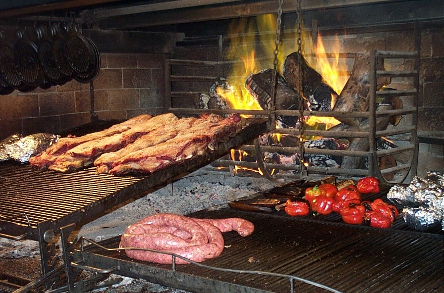alt=Meja dengan potongan daging lembu Argentina, wain, sos dan rempah.