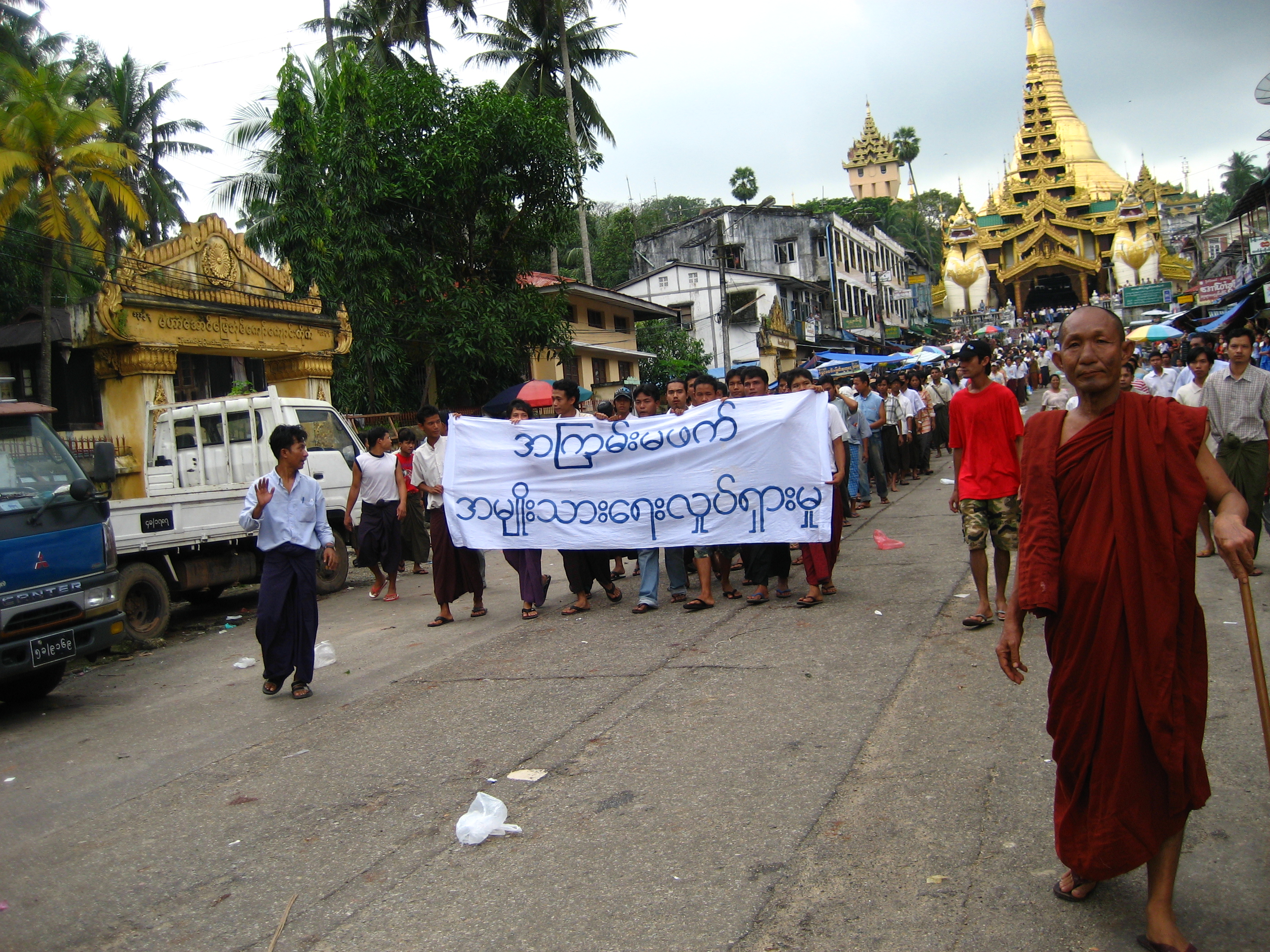 Para penunjuk perasaan di Yangon semasa Revolusi Saffron 2007 dengan sepanduk yang bertulis tanpa kekerasan: gerakan kebangsaan dalam bahasa Burma. Di latar belakang ialah Pagoda Shwedagon.