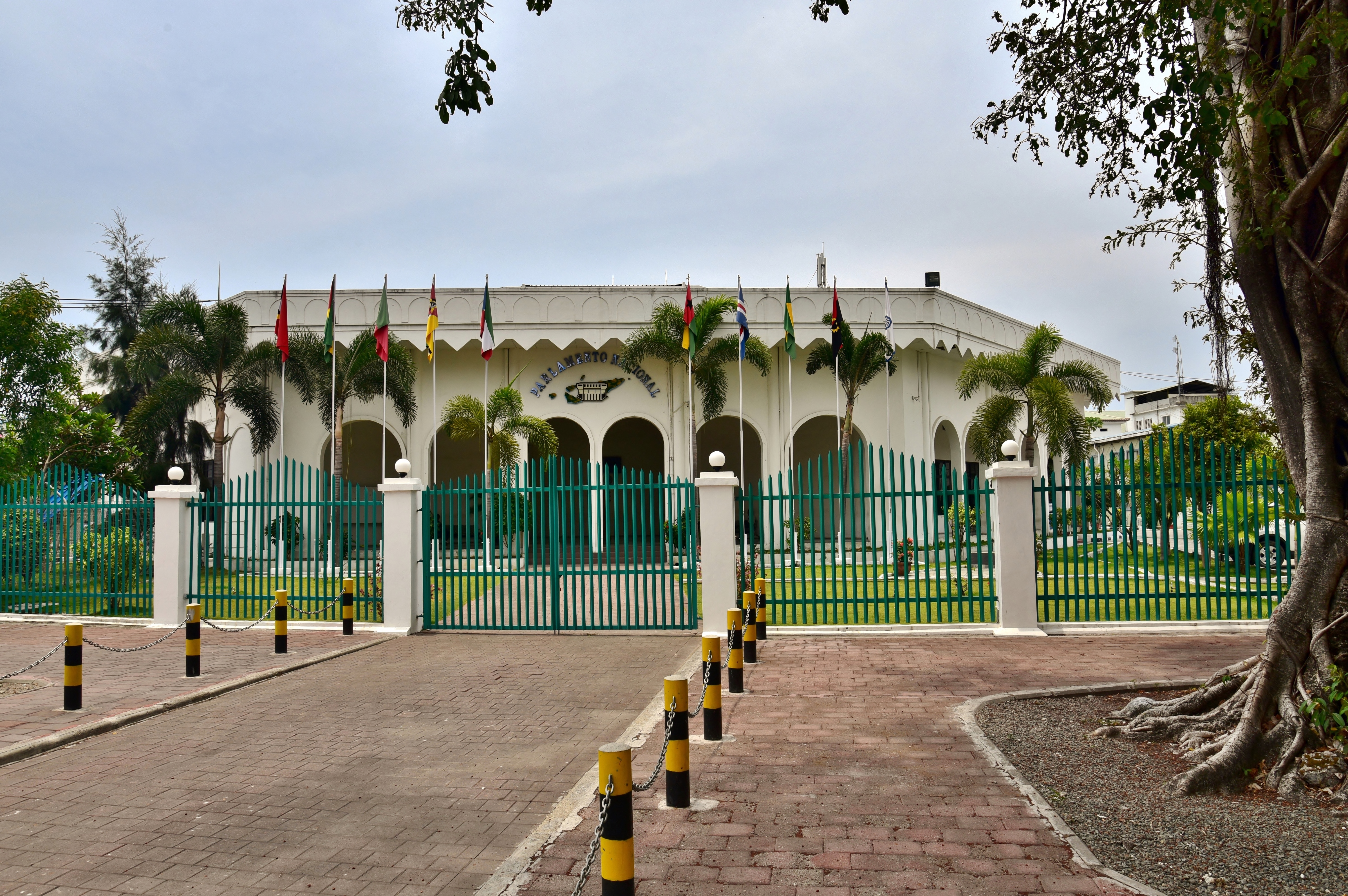 Parlemen Nasional, dengan bendera-bendera Komunitas Negara-Negara Berbahasa Portugis di depannya, melambangkan komitmen terhadap kerjasama internasional dan sistem parlementer.