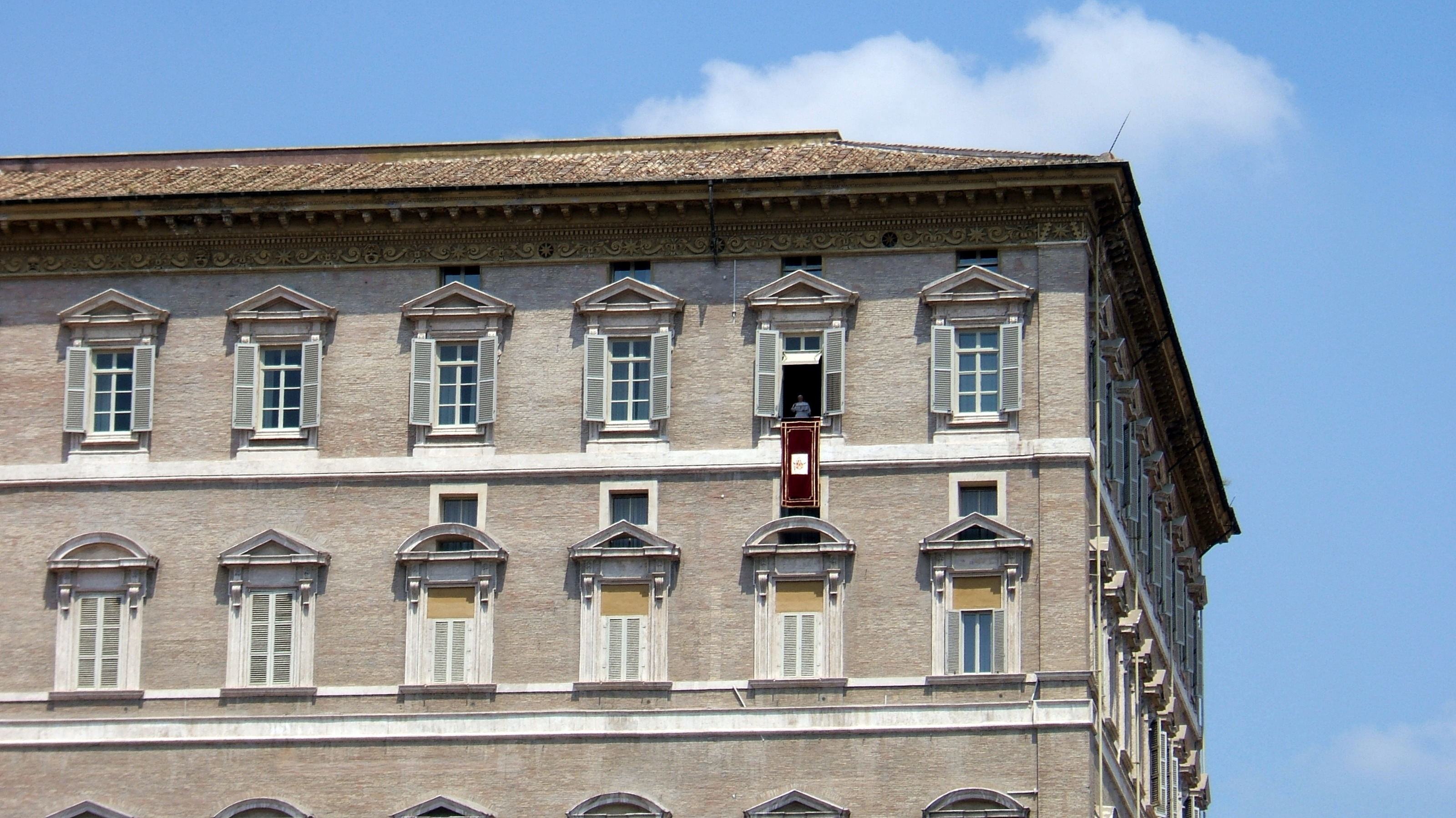 教皇の公邸であるバチカン宮殿(Palazzo Apostolicoパラッツォ・アポストリコイタリア語)。ここでは、中央の窓枠から垂れ下がる栗色の旗で示された窓にベネディクト16世がいる。