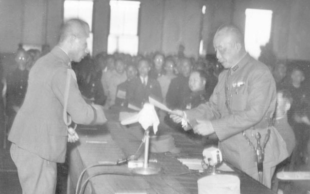 Jeneral Chen Yi (kanan) menerima resit Perintah Am No. 1 daripada Rikichi Andō (kiri), gabenor jeneral Jepun terakhir Taiwan, di Dewan Bandaraya Taipei