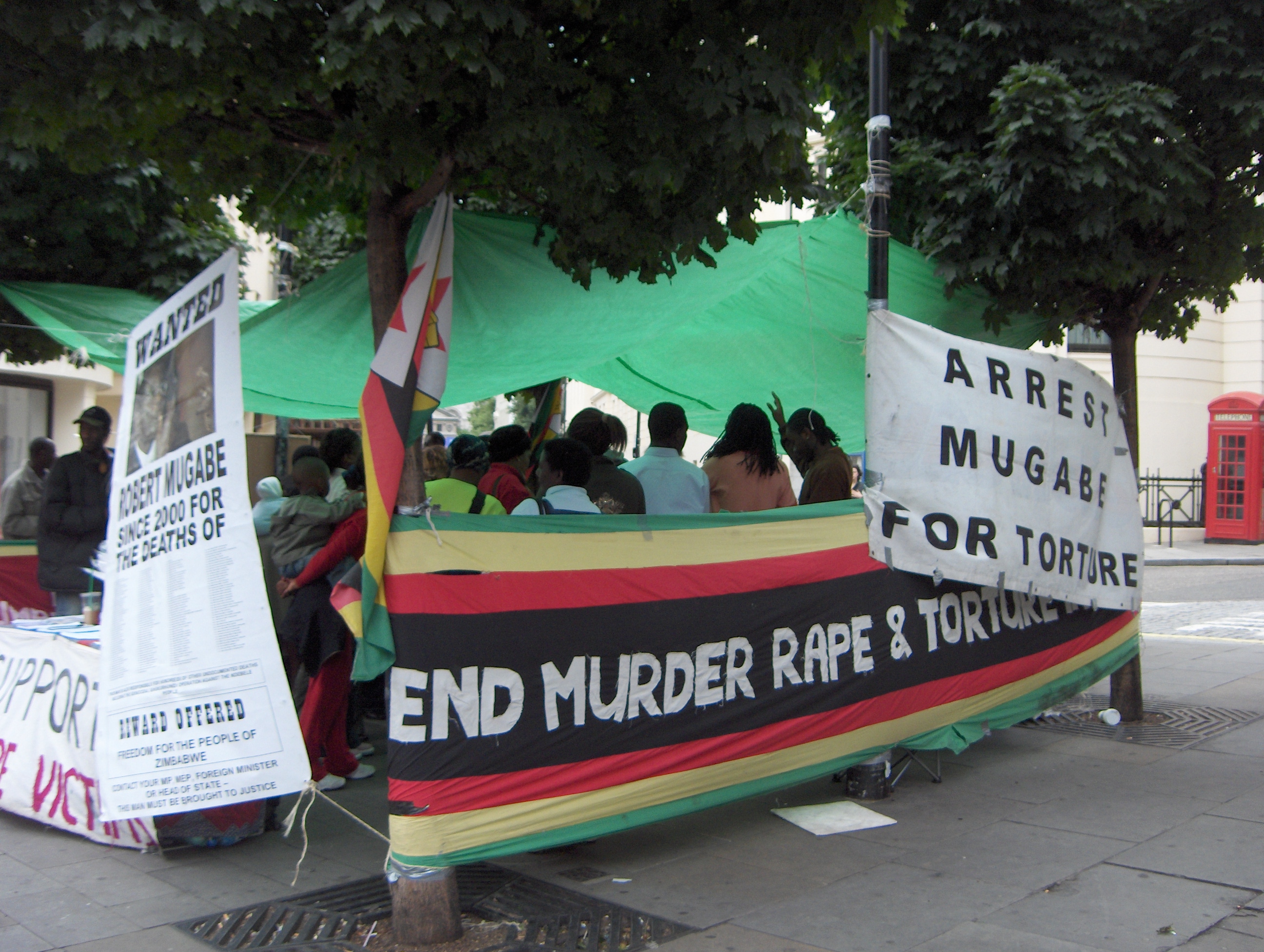 Satu demonstrasi di London menentang Robert Mugabe. Bantahan tidak digalakkan oleh polis Zimbabwe di Zimbabwe.