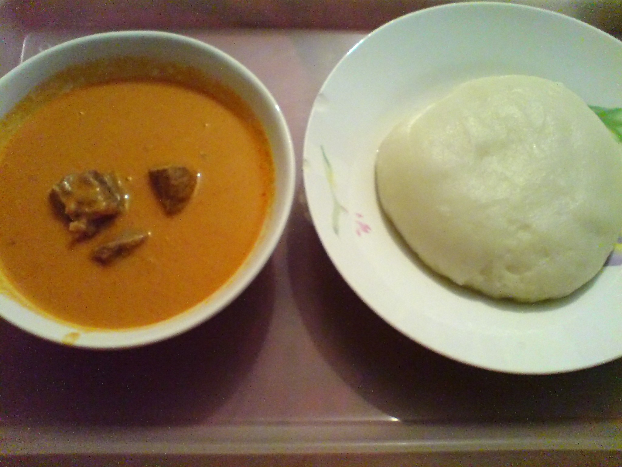 A plate of fufu (right) accompanied with peanut soup, common in West African cuisine.