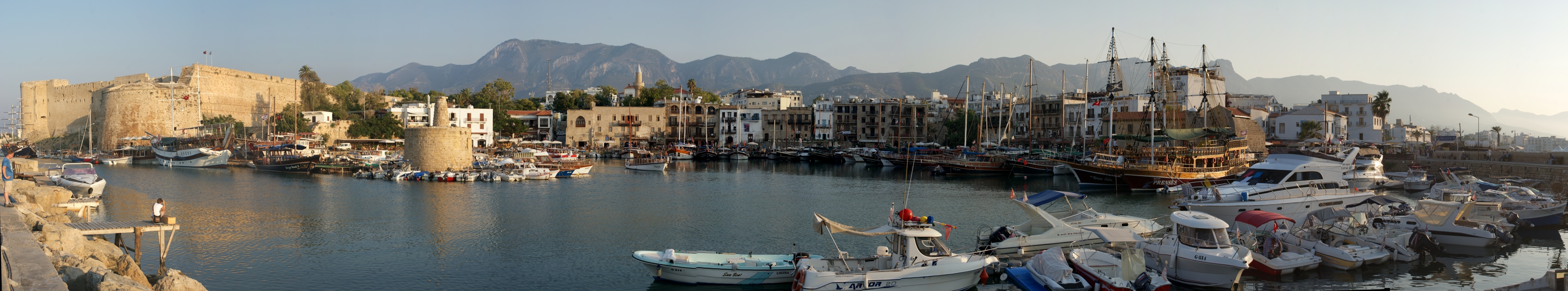 Pemandangan panorama Pelabuhan Kyrenia, dengan Kastel Kyrenia era Venesia di paling kiri, dan Pegunungan Kyrenia di latar belakang