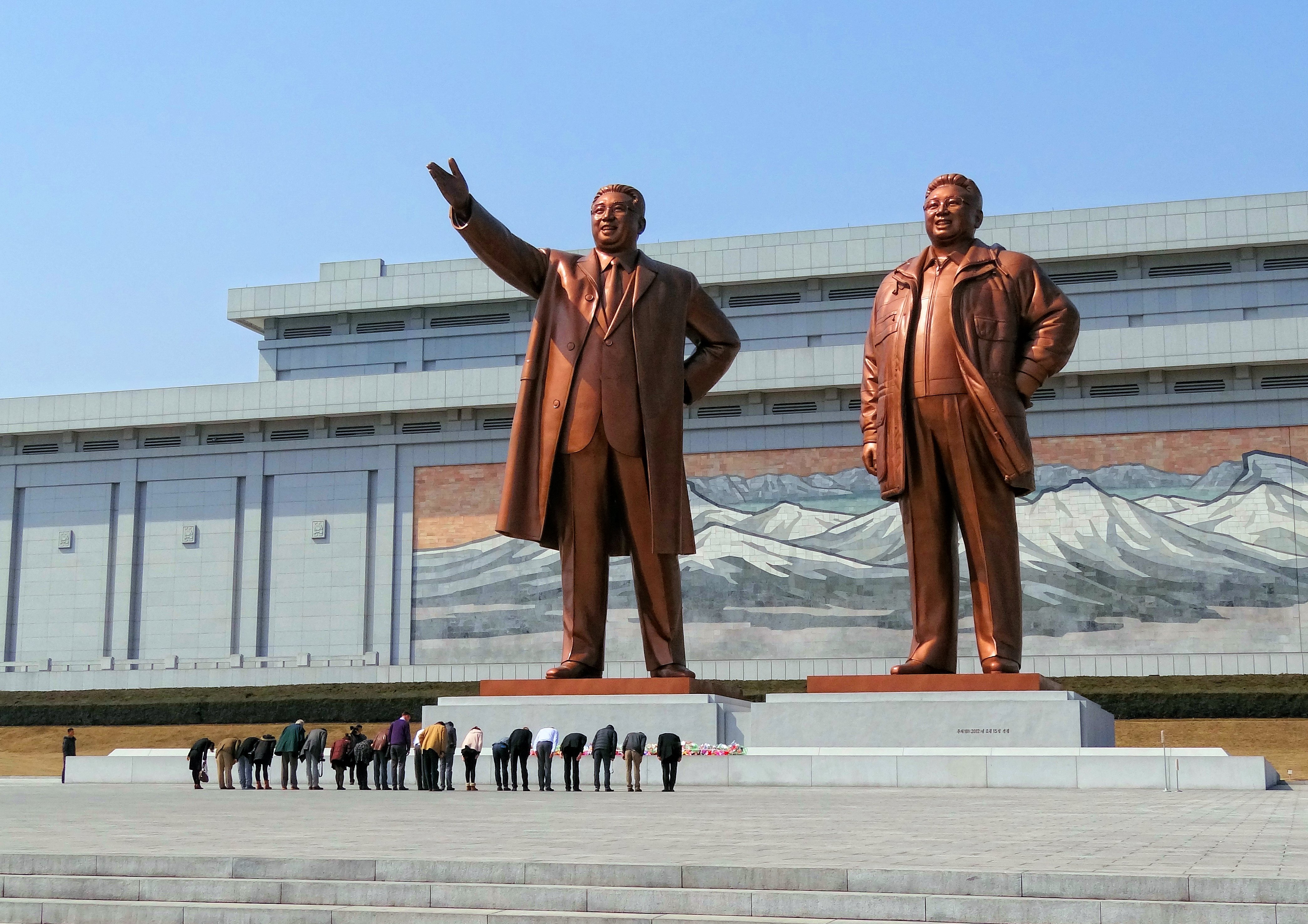Warga Korea Utara memberi hormat pada patung Kim Il-sung (kiri) dan Kim Jong-il di Monumen Agung Bukit Mansu
