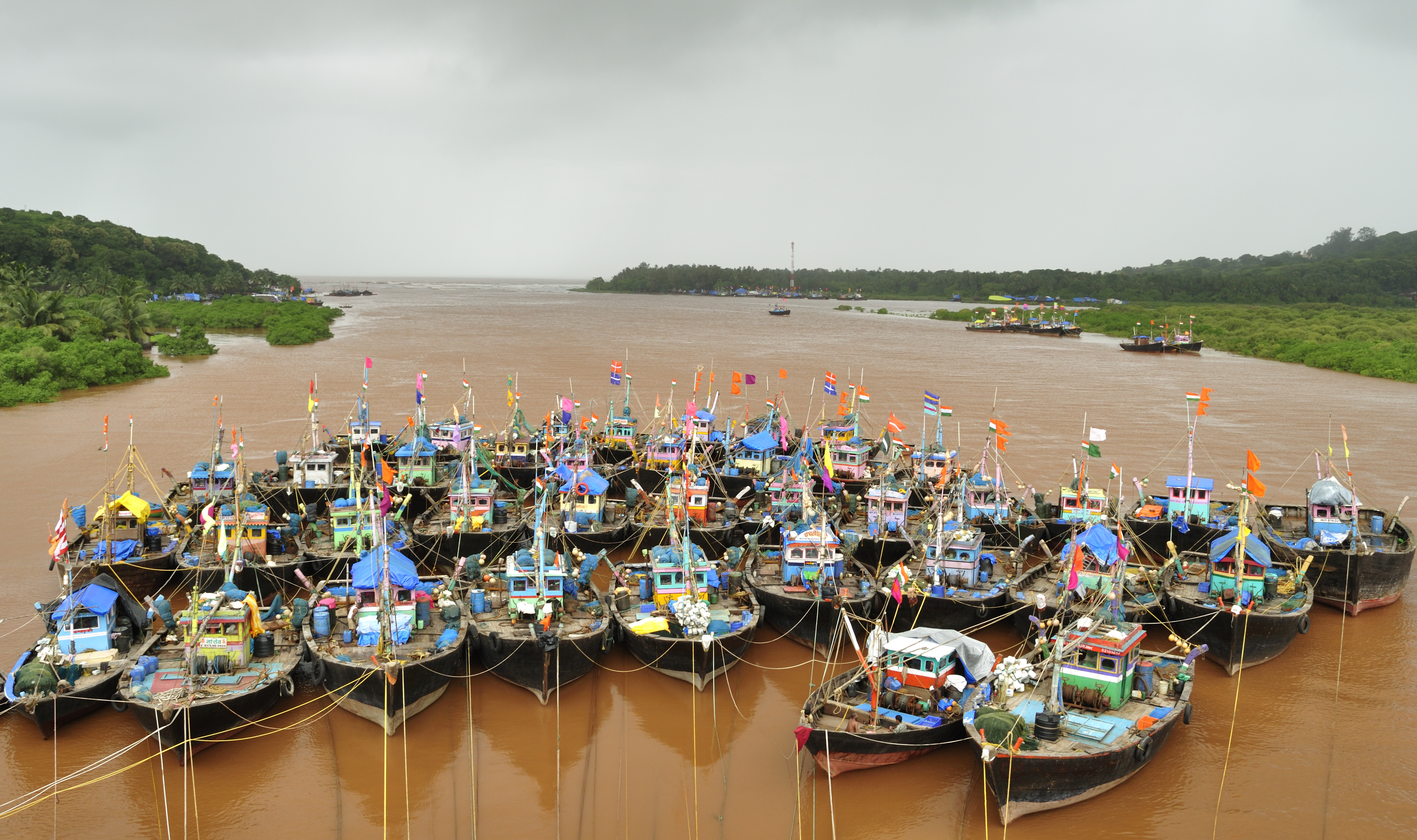 Bot nelayan yang diikat bersama di anak sungai pasang surut di kampung Anjarle, Maharashtra