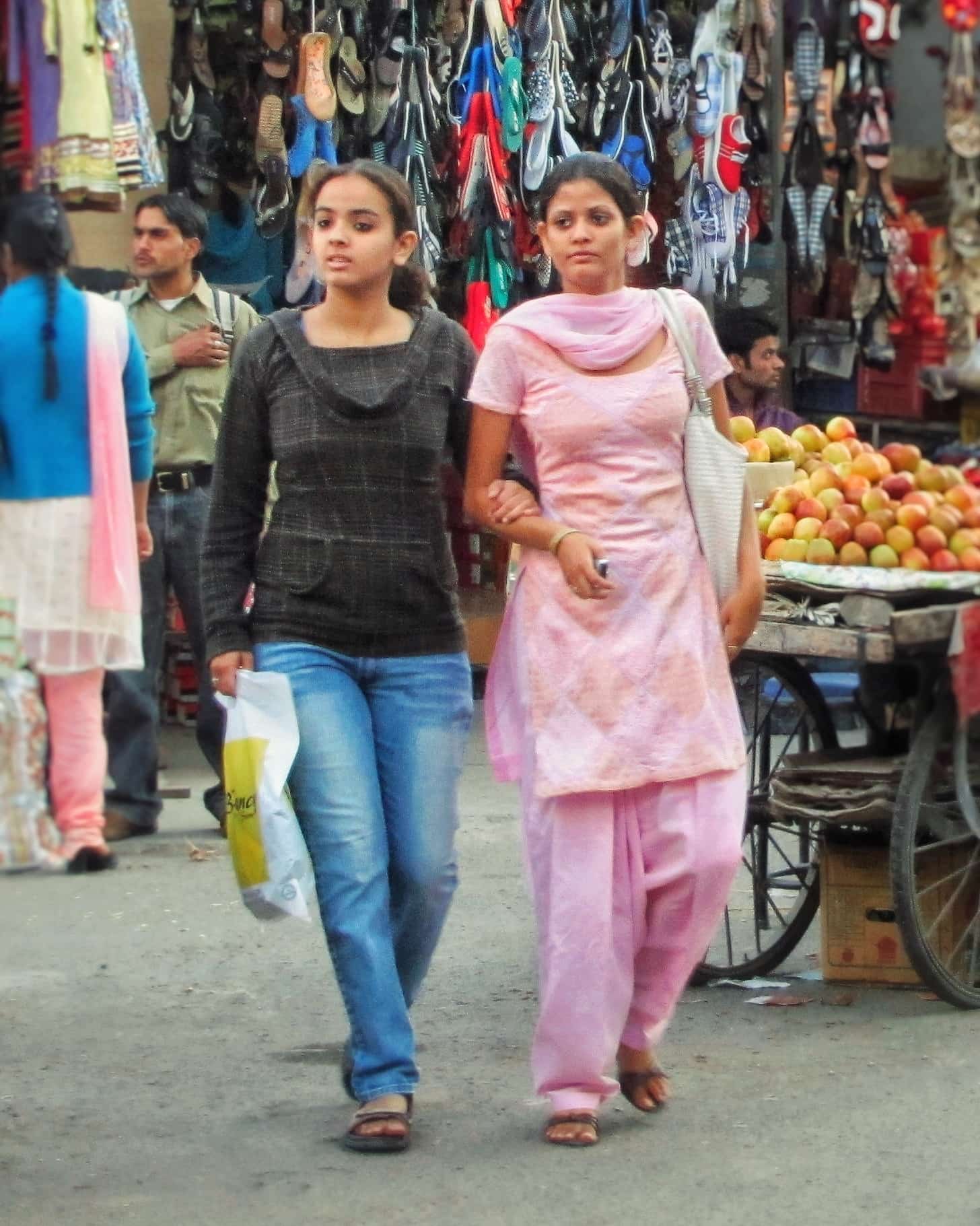 Wanita (dari kiri ke kanan) mengenakan churidar dan kameez (membelakangi kamera), jeans dan sweater, serta shalwar kameez berwarna merah muda